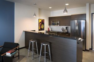 306 Main Apartments kitchen with dark cabinets and black countertops featuring stainless steel appliances and metal stools