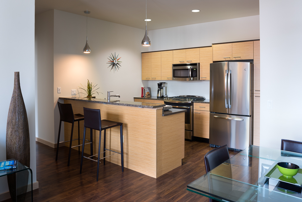 Modern clean dark countertop kitchen apartment with light wood cabinets