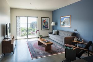 306 Main Apartments Living room with dark wood floors, dark blue accent wall behind the couch and sliding glass door to balcony