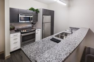 kitchen for apartment with dark cabinets stainless steel appliances and grey granite counter tops