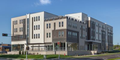 exterior of cream, white and gray four story retail and apartments from across the street