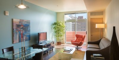 Living space with dark wood floors, light blue accent wall and dining area