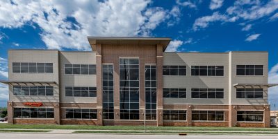 multi-story office building with large windows, brown colored bricks and light brown siding.