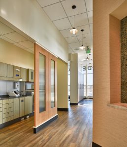 Dental Clinic hallway with light orange accent walls, wood flooring and entrance to dental lab