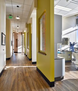 Dental Clinic hallway with yellow accent walls, wood flooring and entrances to dental operatories