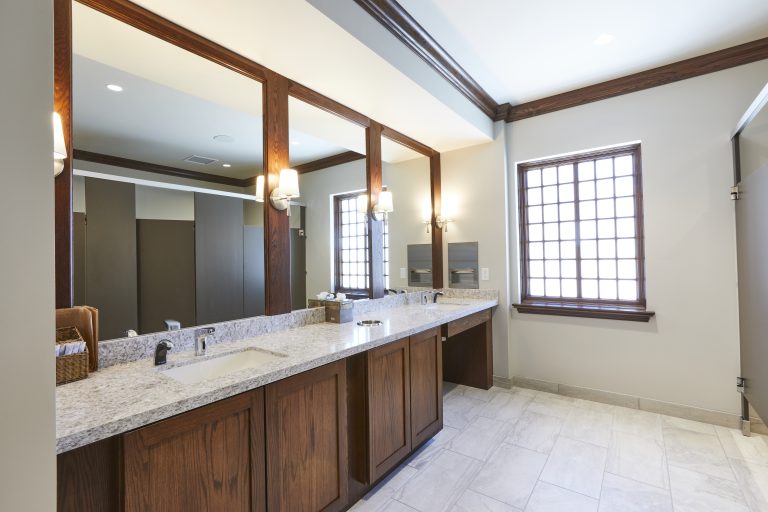 Restroom mirrors and sink with wall sconce lighting, and lattice windows