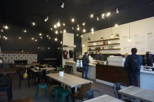 Espresso bar with high exposed black ceilings and strings light throughout the bar and seating area