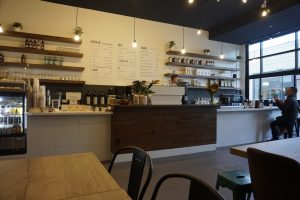 Espresso bar with white tiles and wood accent in front of cash register