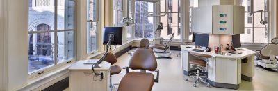 Dental operatory with brown leather chairs, arched windows and dental equipment