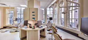 Open Dental operatory space with multiple dental chairs, equipment, and arched windows