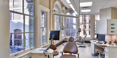 Dental operatory with brown leather chairs, arched windows and dental equipment