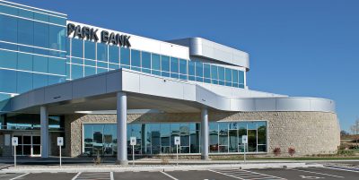 Modern commercial building with large glass windows. The structure features a contemporary design with a combination of stone and metal elements.