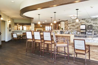 A senior living facility bar with stone accents, hanging lights, and stools