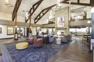 Senior Living facility lobby with vaulted ceilings, natural floor to ceiling fireplace, wood floors and lounge seating