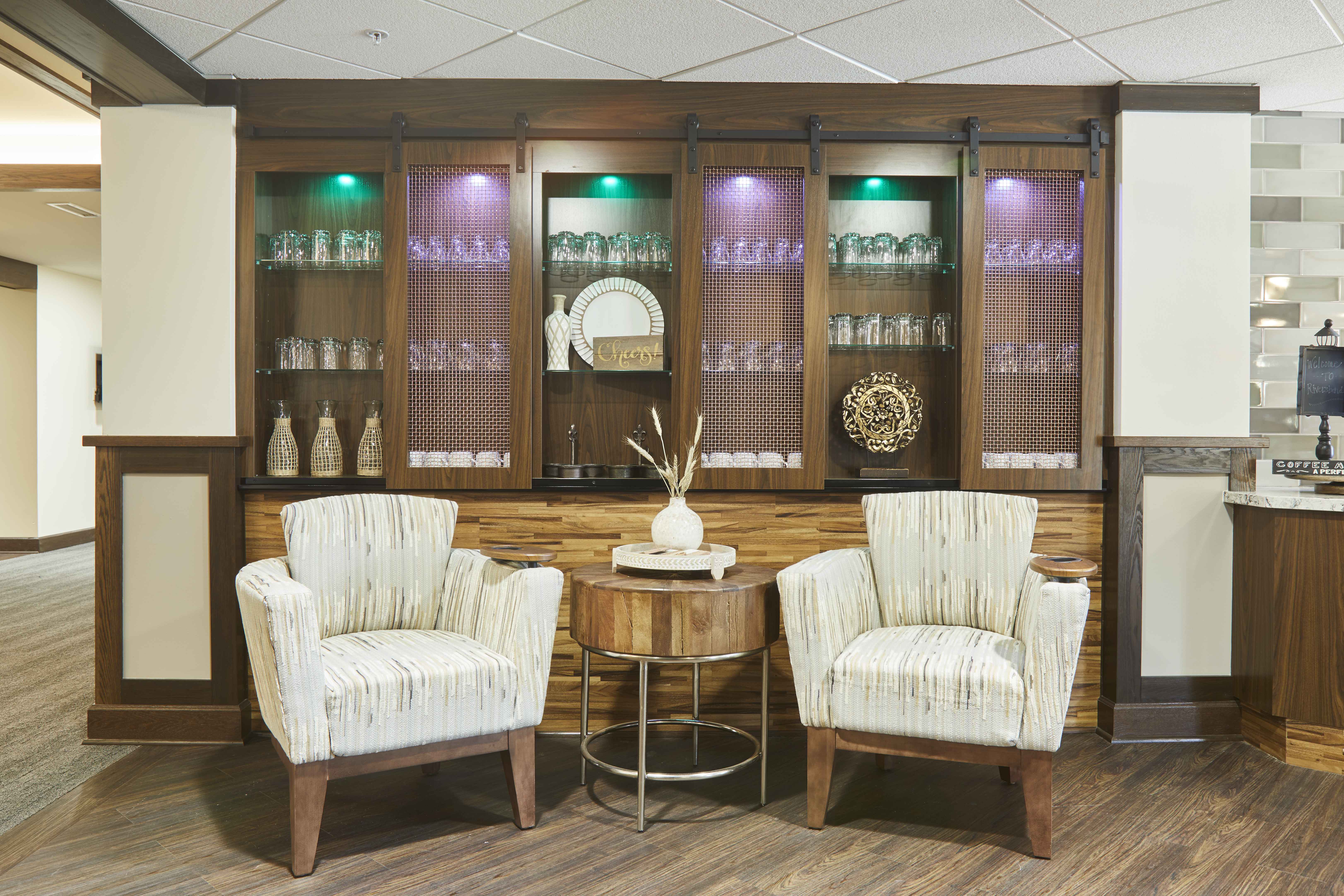 Senior Living bistro waiting area with two sand color lounge chairs and wood built in wall cabinets