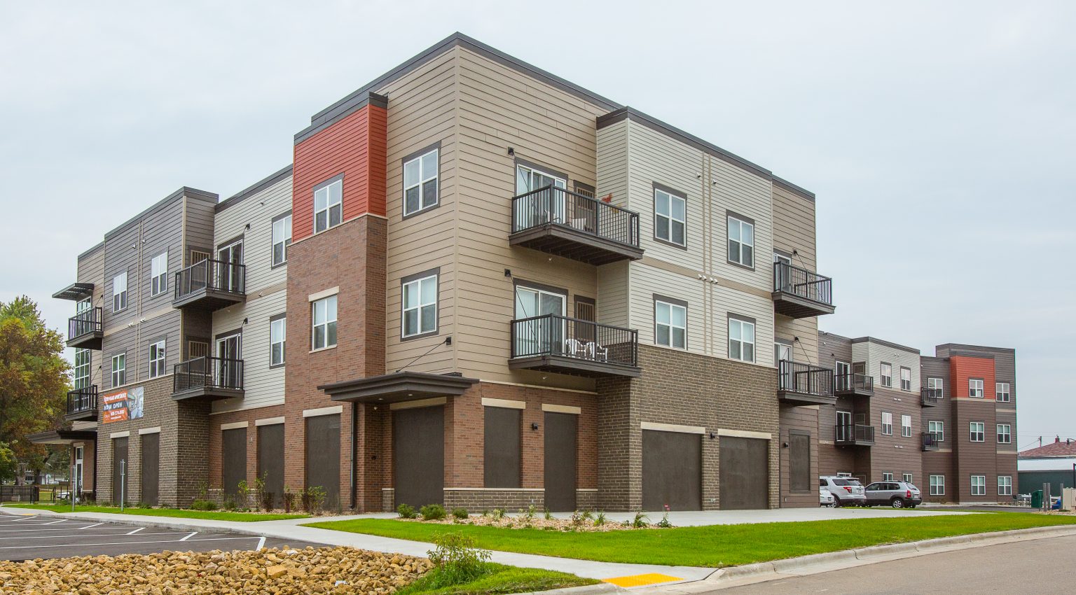 exterior of apartment building with brown siding and burnt orange accents, and brown garage doors for underground parking