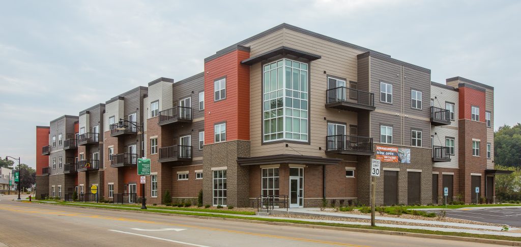 wide exterior of apartment building with brown siding and burnt orange accents