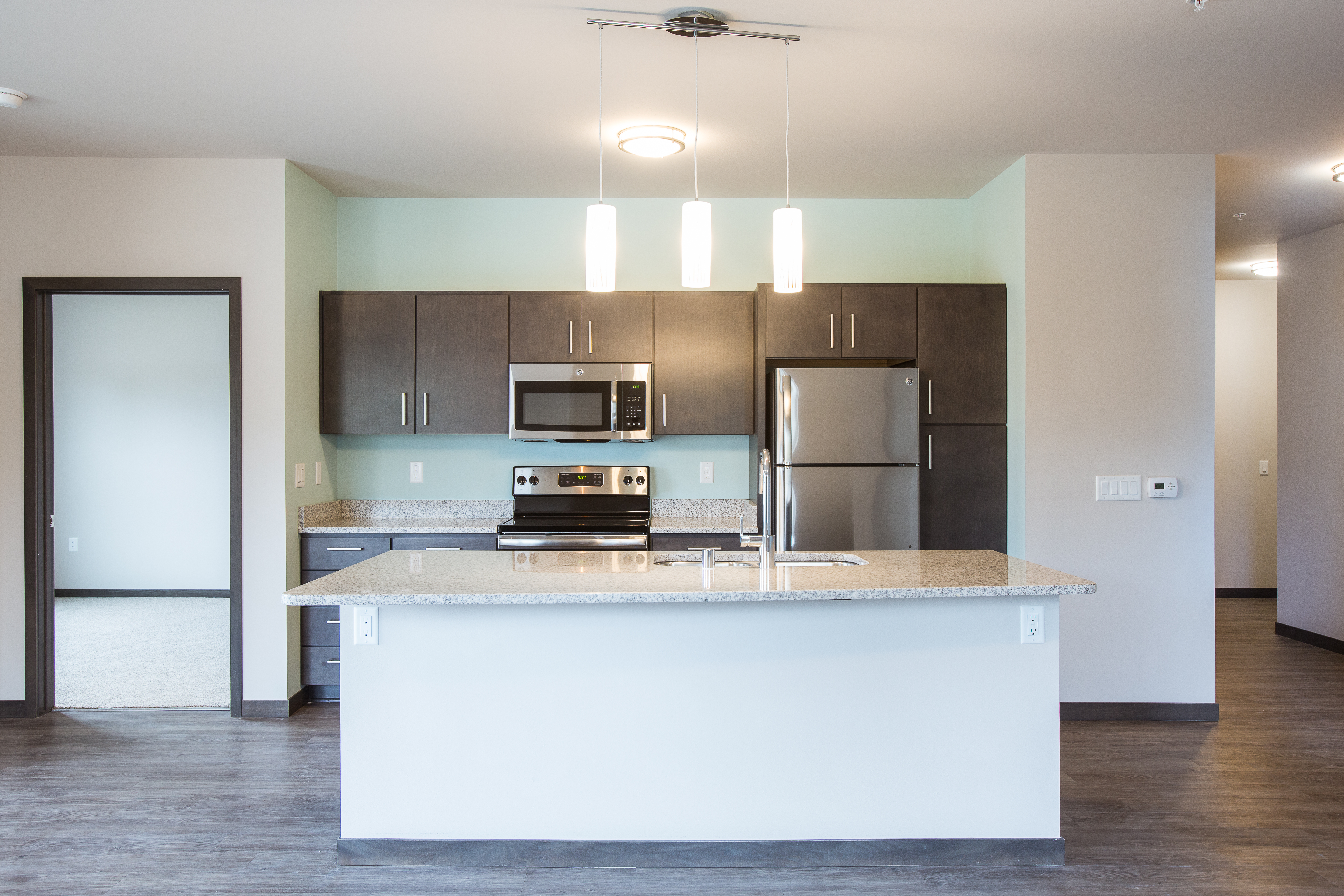 straight on view of kitchen with dark cabinets and a white island with granite countertops