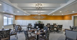 Senior living facility dining room with white paneled walls and an orange accent wall