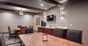 Senior living activities room with a monitor on the wall and wood top table seating