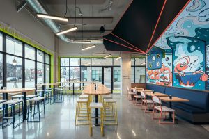 Sushi Restaurant with tables for seating, concrete flooring and mural wall with orange and blue accents