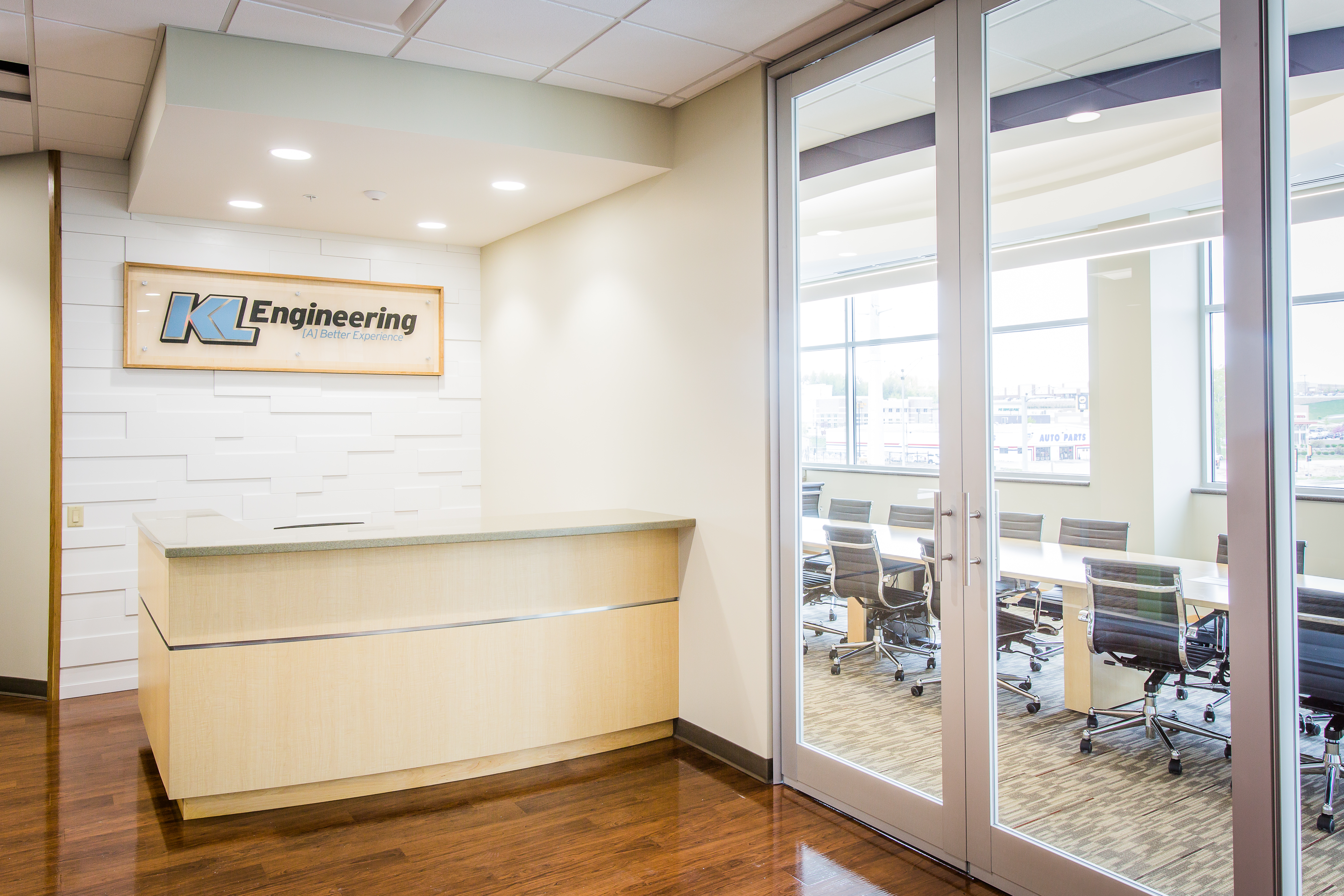 Office lobby with reception desk with white stone accent wall, KL Engineering sign and glass doors into a conference room