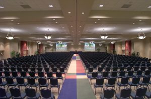 convention center with black seating chairs and two projector screens in the front