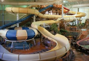 Cream colored indoor water slides that twist around the space, with blue accents on the a donut bowl slide