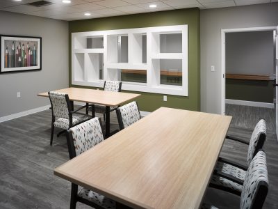 wood top tables and chairs with green accent wall with built in shelving