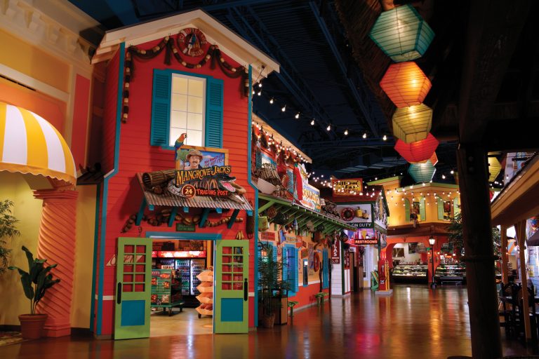 interior of the water park with a small town built featuring exteriors of buildings, dark floors and lantern lights hanging from the ceiling