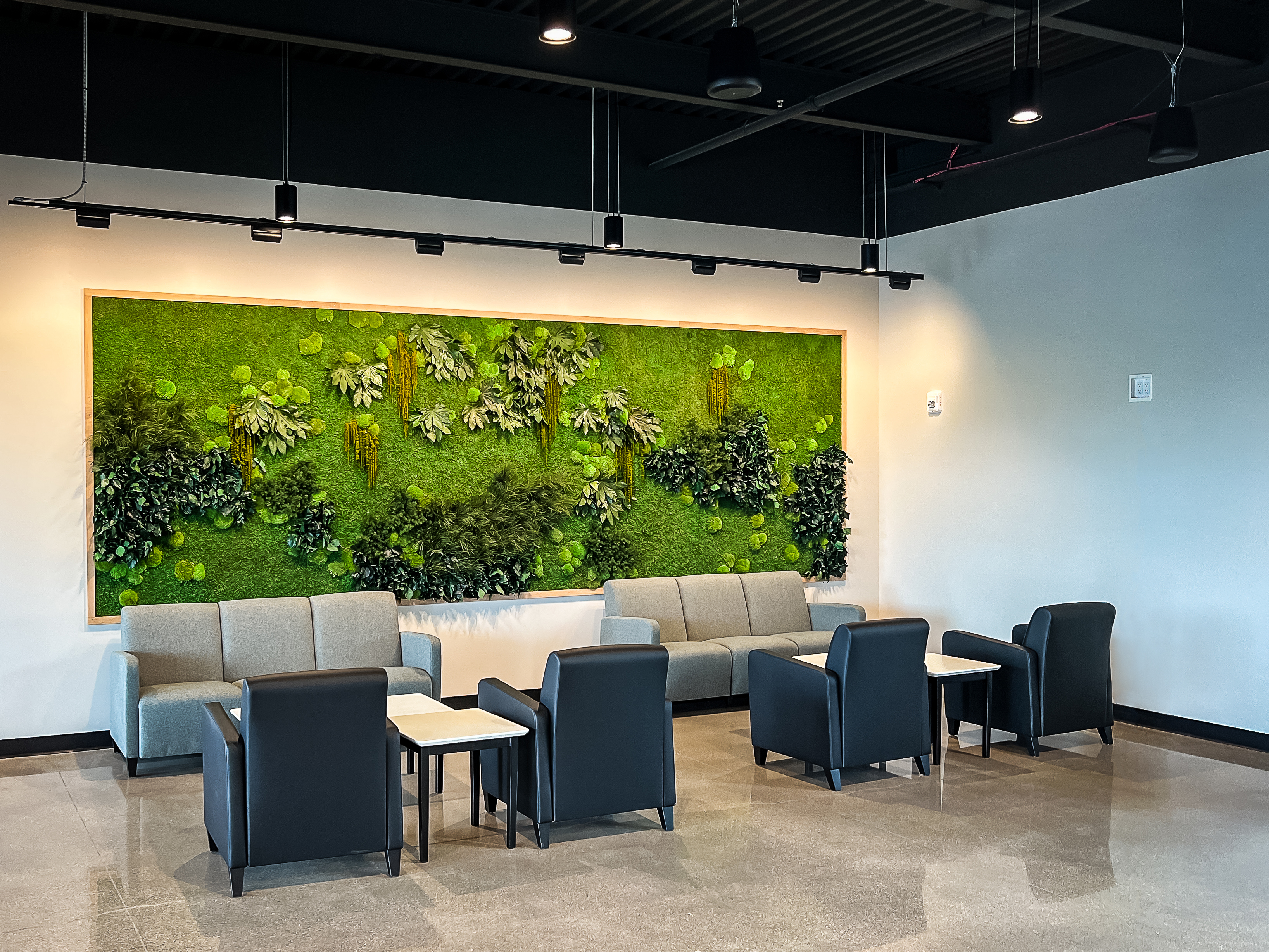 Waiting lounge area with seating and mossy green backdrop