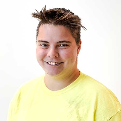 Headshot of a female carpenter wearing a neon green construction shirt.