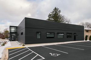 Back of Dental office building with parking lot and black exterior siding