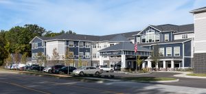 A three-story senior living facility with dark blue and white siding.