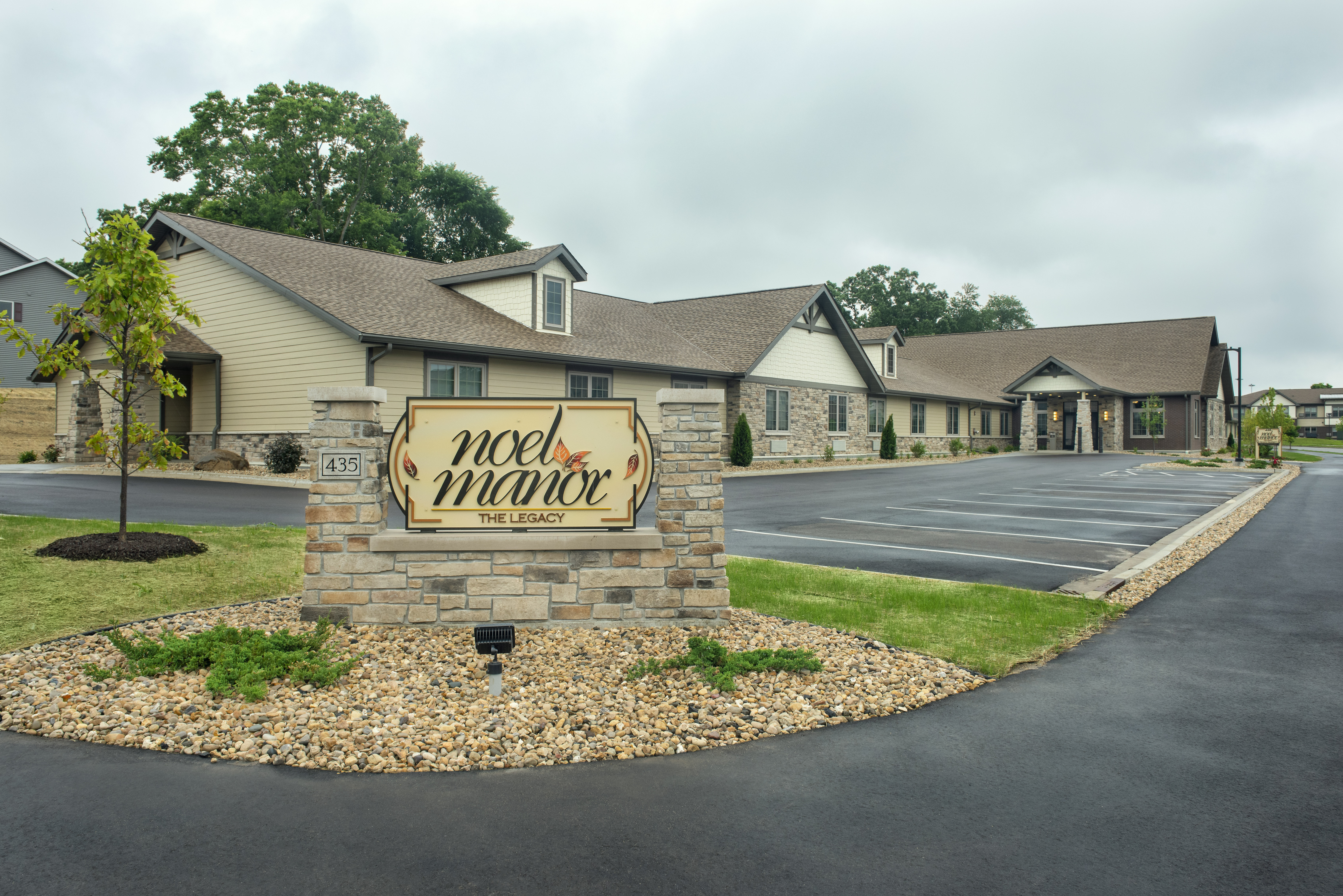 Exterior of retirement living with brick stand signage and cream and green colored wood sign