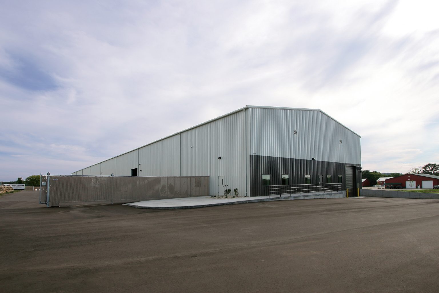 A large, modern warehouse building with a metal exterior. It has multiple loading docks and a spacious paved area