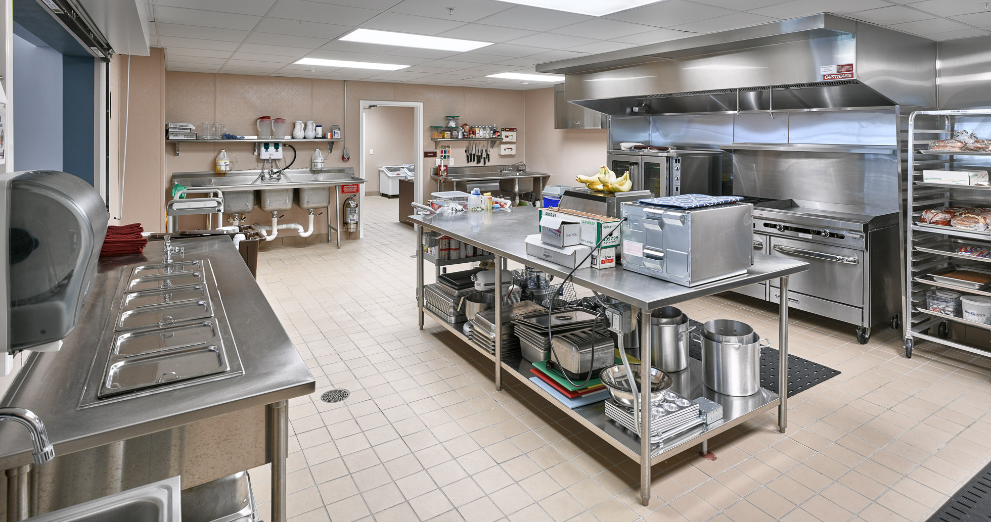 Senior living industrial kitchen with stainless steel equipment and island