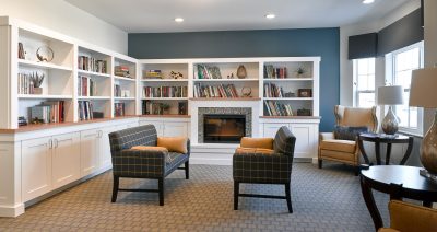 Library with two couches for seating next to the fireplace and white bookshelves