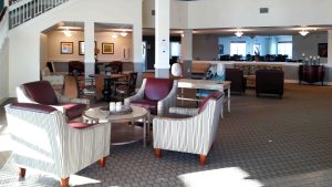 Lobby of Senior living facility with armchair sofas, dark carpeting and expansive ceilings