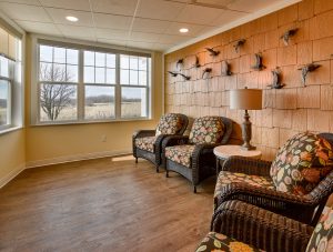 Senior living seating area with wood floors and view wrapped walls that allow people to look outside