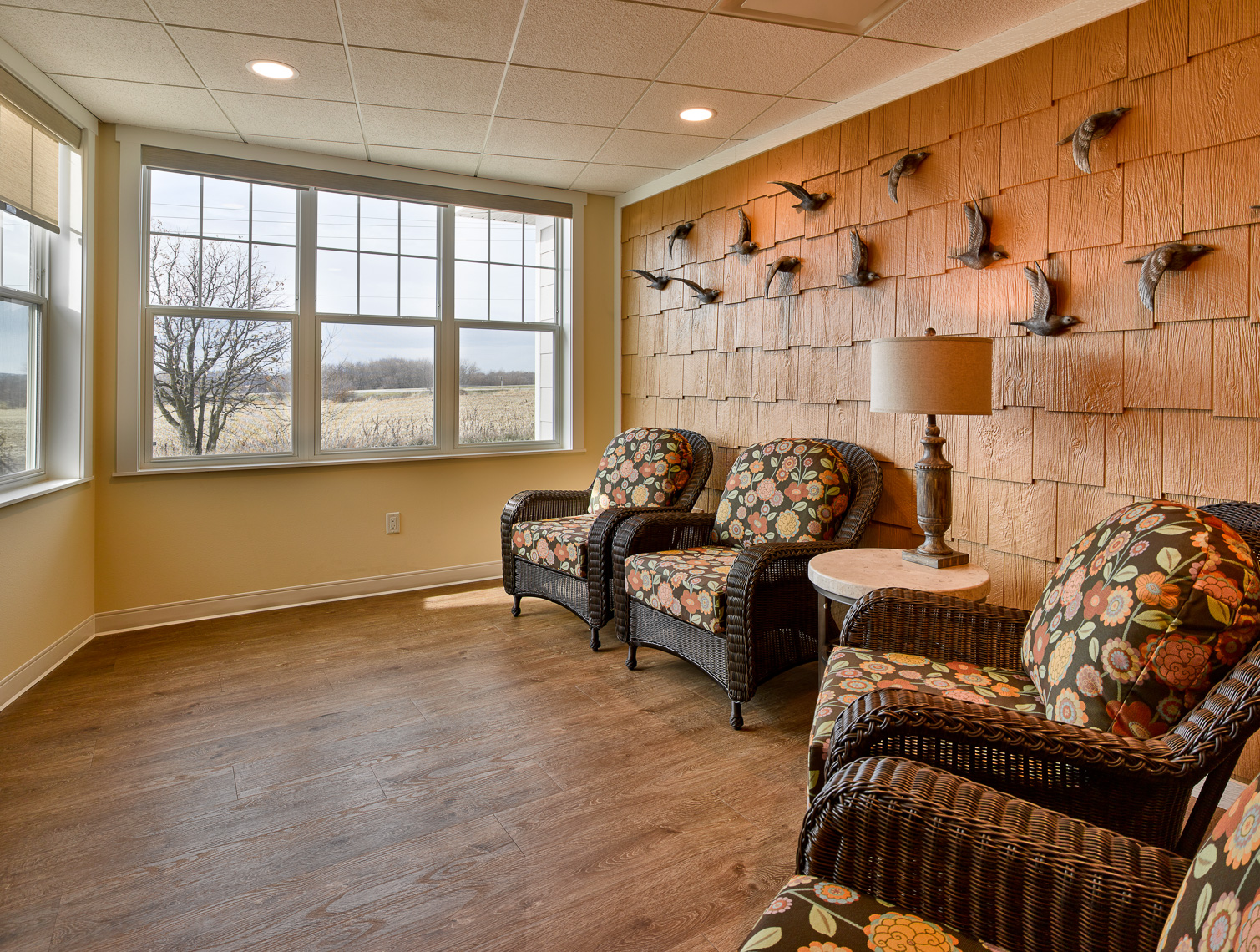 Senior living seating area with wood floors and view wrapped walls that allow people to look outside