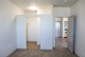 Apartment bedroom with view of the closet opening and open door