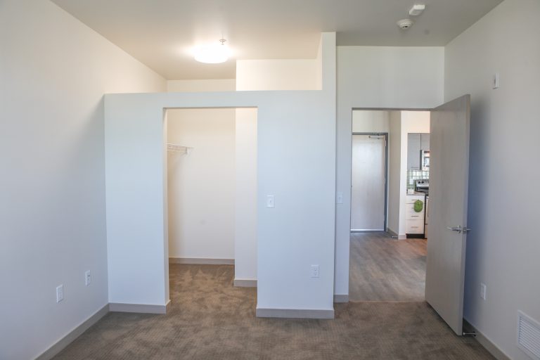 Apartment bedroom with view of the closet opening and open door