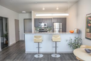 kitchen with island view, bright overhead light dark cabinets, island stools and stainless steel appliances