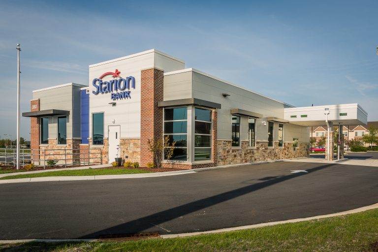 A modern bank building with a flat roof and a mix of brick and stone exterior, with large windows and a drive-thru.