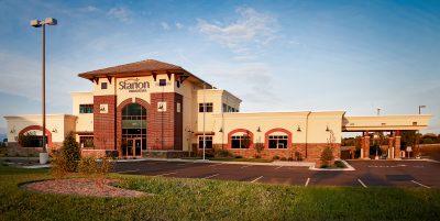 exterior of bank with tan and brick exteriors, large windows, and a covered drive-thru area.