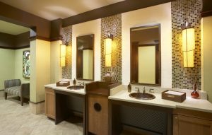 Restroom sink and mirrors with granite countertops and contemporary lighting