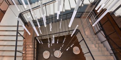 Looking down a wrapped staircase with hanging lights down the middle