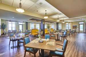 Senior living dining area with wood top tables, yellow booth seating and wood flooring