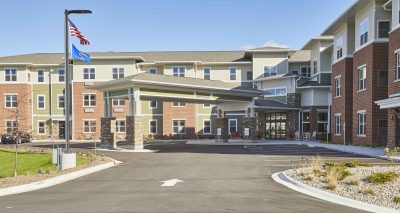 Exterior of senior living facility with drive up covered entrance with brick accents